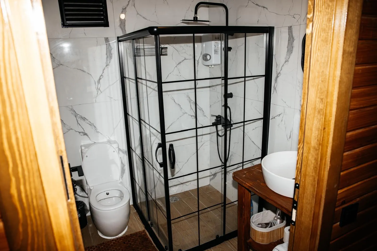 Siyah çerçeveli duş kabini ve ahşap lavabo dolabı