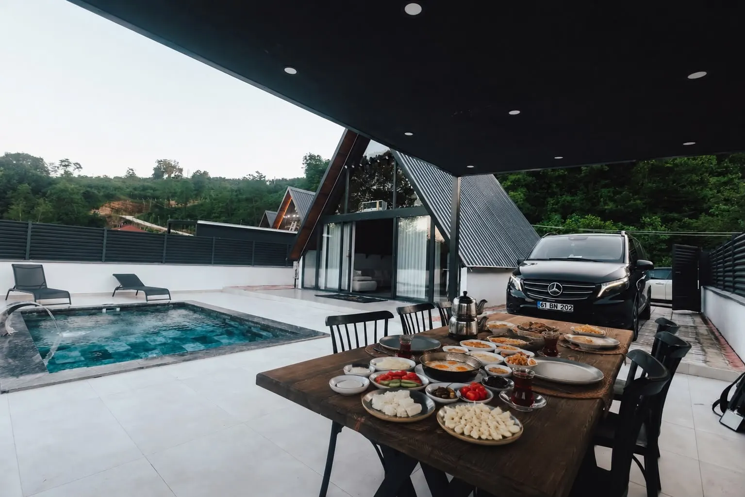 Pergola altında kurulmuş kahvaltı masası, havuz başında